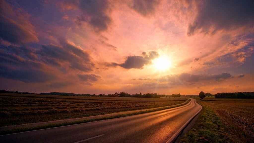 A serene sunset over a winding country road with colorful clouds and vast fields. Symbolizing what reiki feels like and perfect for relaxation, meditation, and mindfulness.