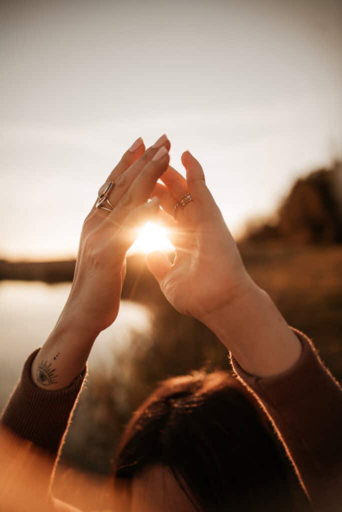 Bright hands performing Reiki energy healing in a serene outdoor setting during sunset, emphasizing relaxation and spiritual connection.